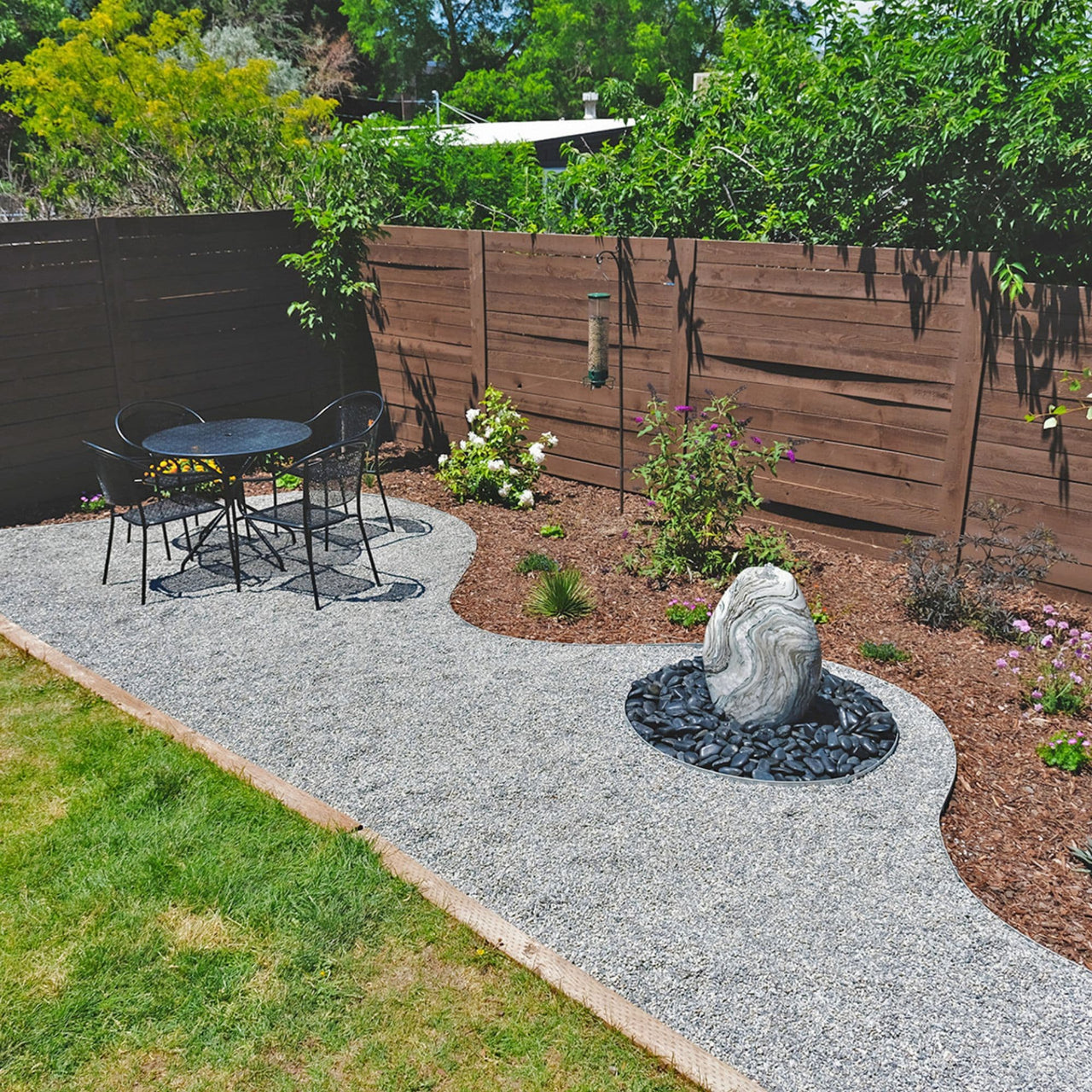 Red Onyx Stone Fountain With Table And Chairs, Wooden Fence Behind