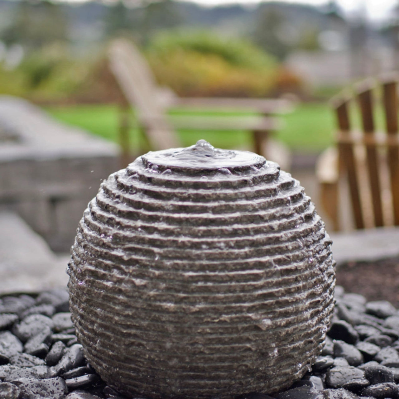 Ribbed Granite Sphere Stone Fountain On Blurry Background
