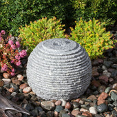 Ribbed Granite Sphere Stone Fountain With Colorful Plant Background