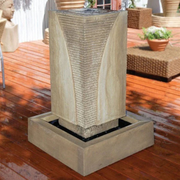 Ribbed Monolith Garden Water Fountain By Gist With Rattan Table And Planters In The Background