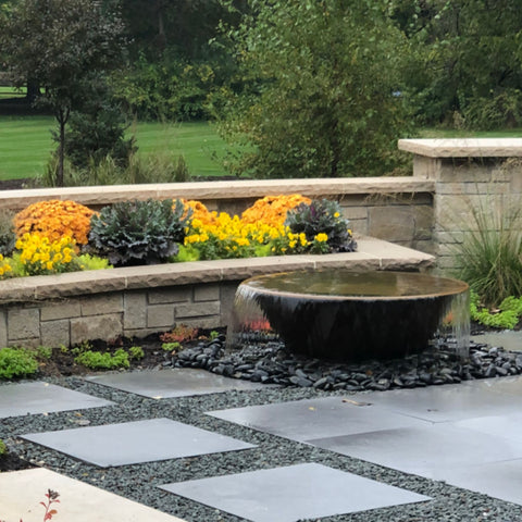 Rustic Sugar Kettle Powder-Coated Cast Iron Fountain On Outdoor Patio Landscape With Stone Wall And Flowers