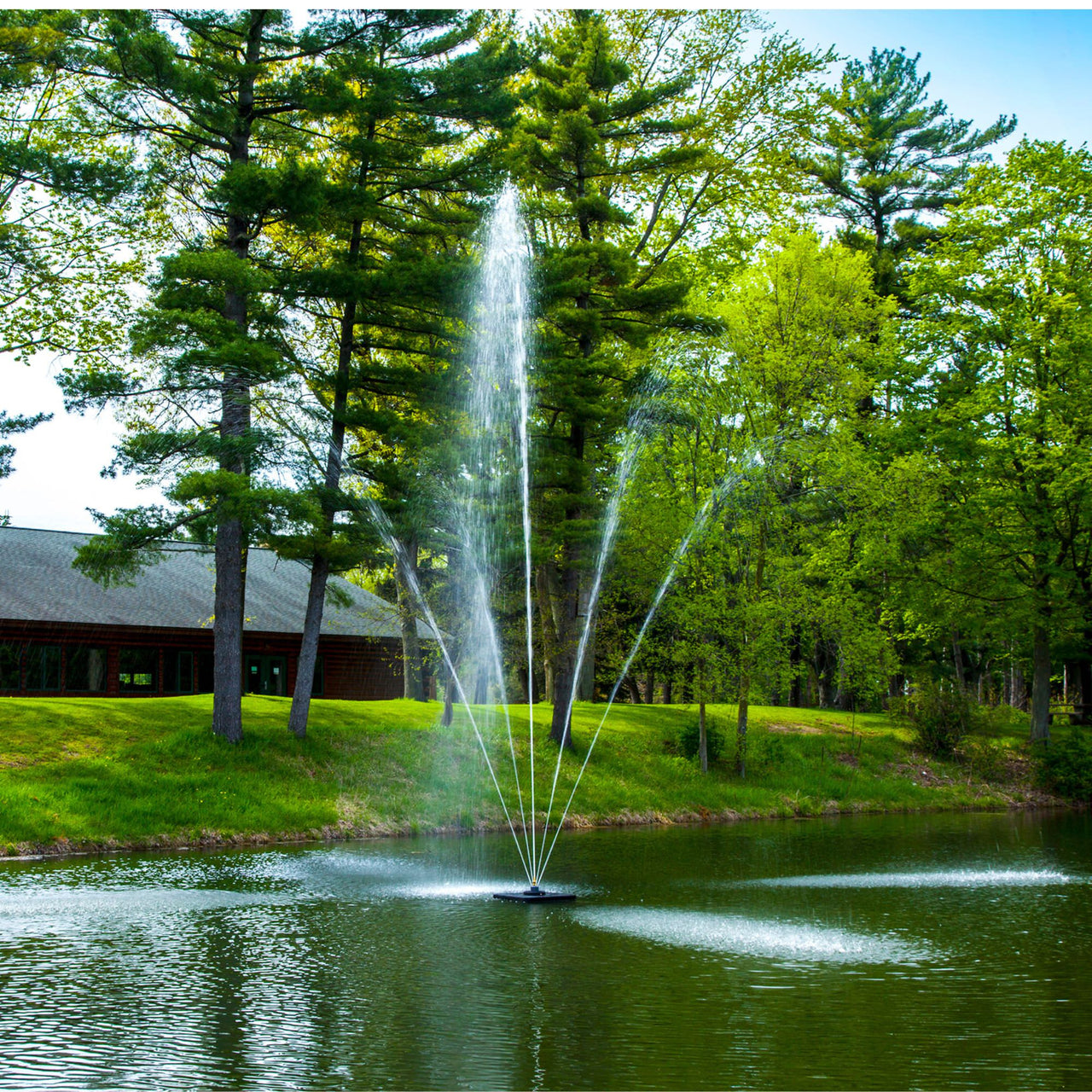 Scott Aerator Clover Pond Fountain On The Water With A House In The Background