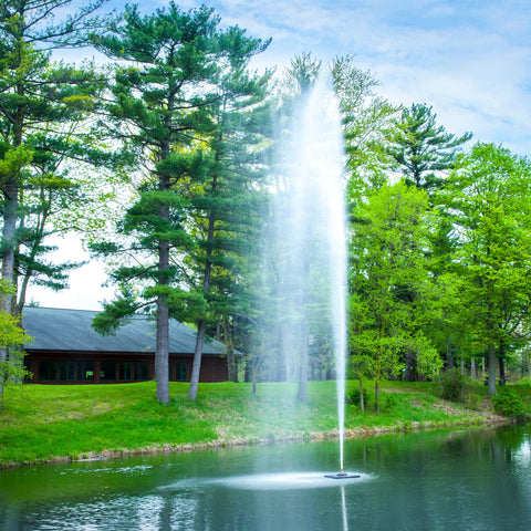 Scott Aerator Gusher Fountain On The Water With Green Trees In The Background