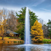 Scott Aerator Gusher Pond Fountain On The Water With Green Trees & A House In The Background