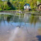 Scott Aerator Aquasweep Max Front Angled View Freestanding In Shallow Water With Houses Trees In The Background