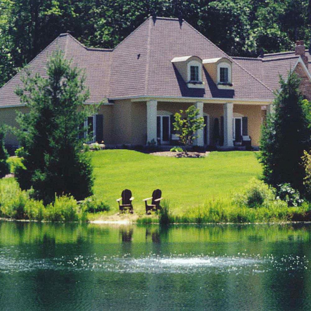 Scott Aerator Bubble Pro Sub-Surface Aerator In The Water Bubbling On The Surface With A House In The Background