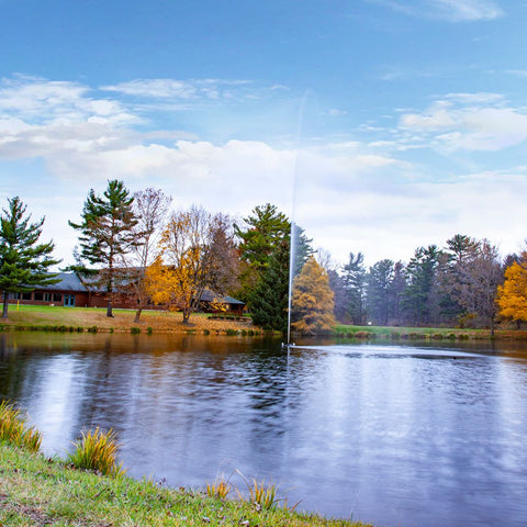 Scott Aerator Jet Pond Fountain On The Water With Colorful Trees & A House In The Background