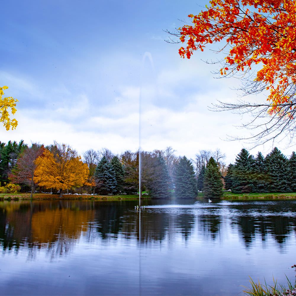 Scott Aerator Jet Stream Pond Fountain On The Water With Colorful Trees In The Background