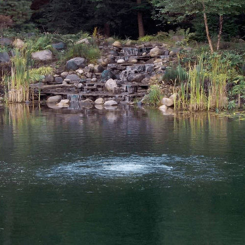 Scott Aerator Solar Pond Aeration System Bubbling On Pond Surface With A Waterfall In The Background