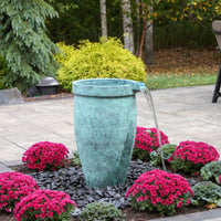 Thumbnail for Single Round Urn Fountain Surrounded By Red Flowers And Trees In The Back