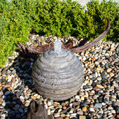 Smooth Ribbed Limestone Sphere Stone Fountain Surrounded By Green Plants