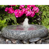 Smooth Round Granite Stone Fountain With Vibrant Flowers And Shrubs Behind
