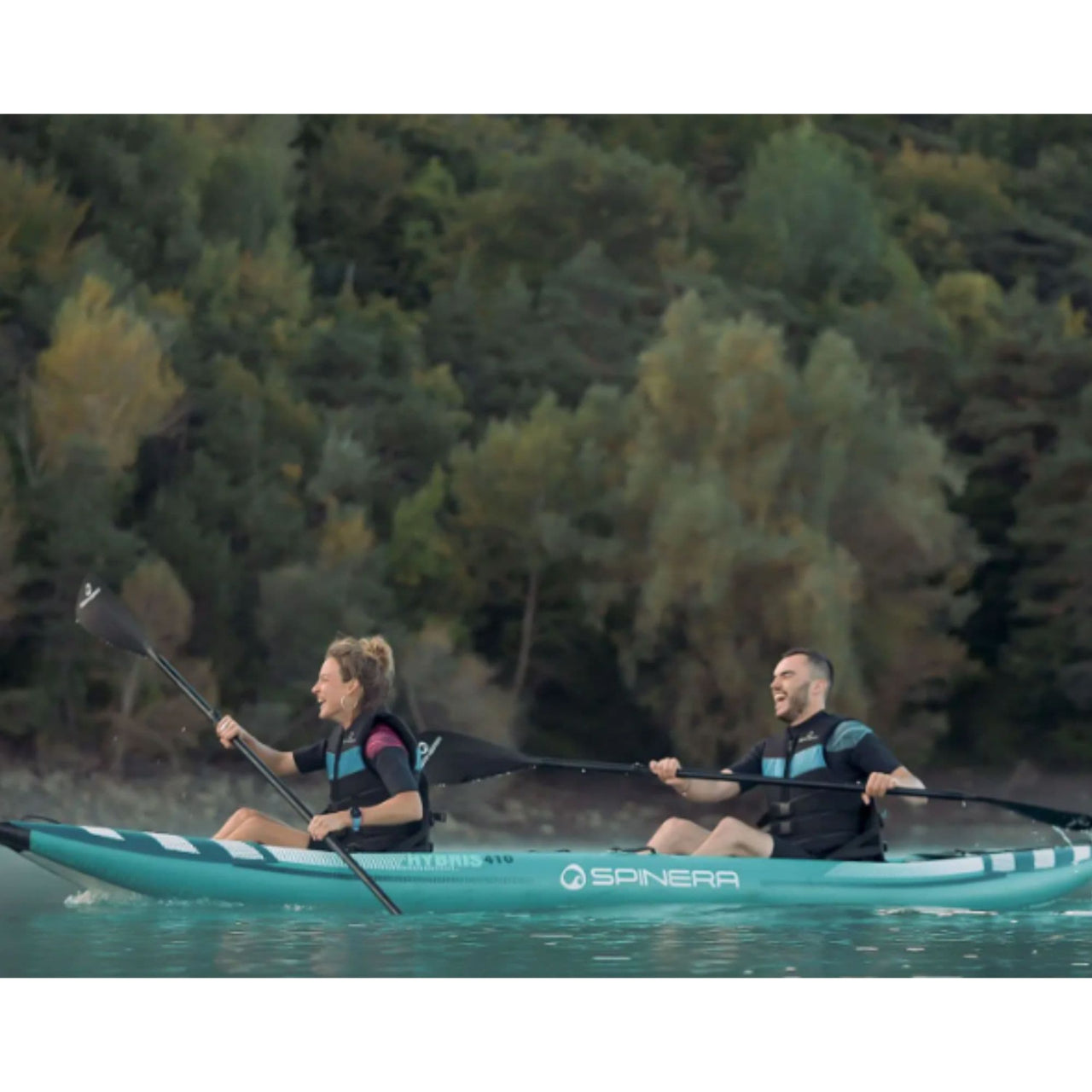 Spinera Hybris 410 Inflatable Kayak With Two People Laughing While Kayaking On Calm Water With Trees Background