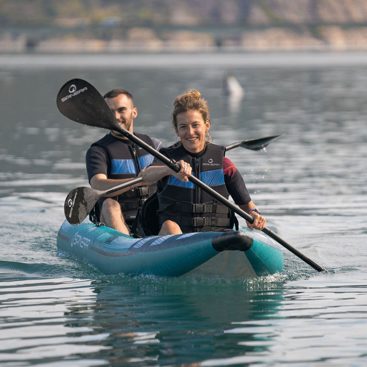 Spinera Hybris 410 With Man And Women Smiling While Paddling On Calm Waters