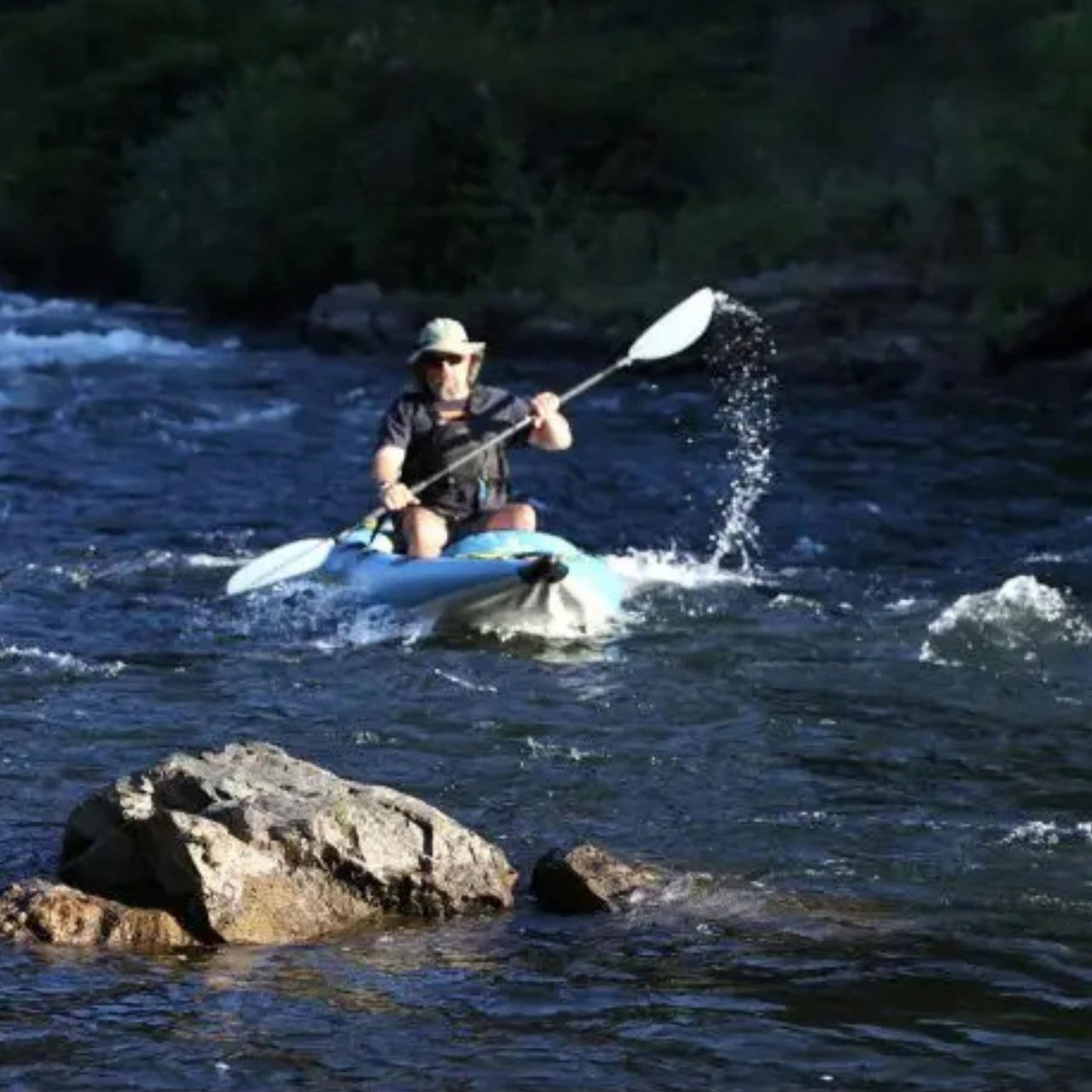 Spinera Kenai 130 With A Man Kayaking In Front Of Big Rock On Fast-Flowing River