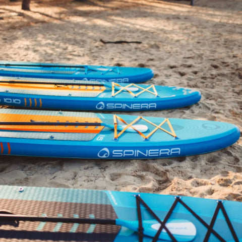 Spinera Lets Paddle 10.10 Paddle Board Lined Up On Sand Shore