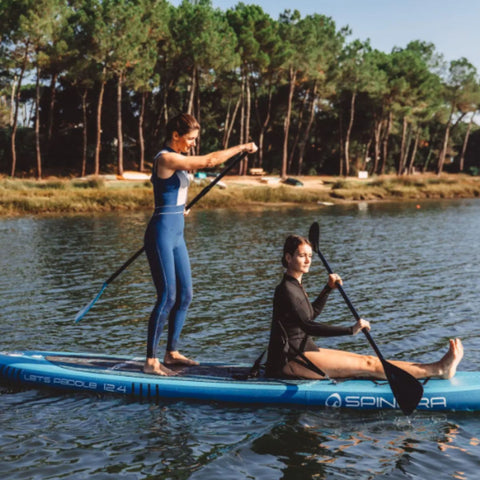 Spinera Lets Paddle 12.4 Paddle Board With One Girl Standing and One Sitting While Paddling Together