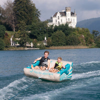 Thumbnail for Spinera Lounger 2 Person Towable With Two Boys Tubing and Big House and Trees at the Back