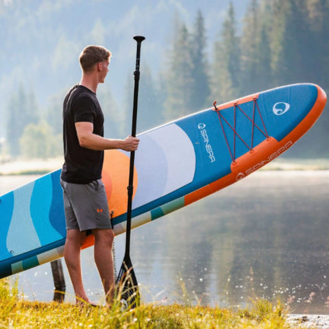 Spinera SUP Supventure Sunrise 12.0 With a Man Holding Paddle and Board Looking at the Water