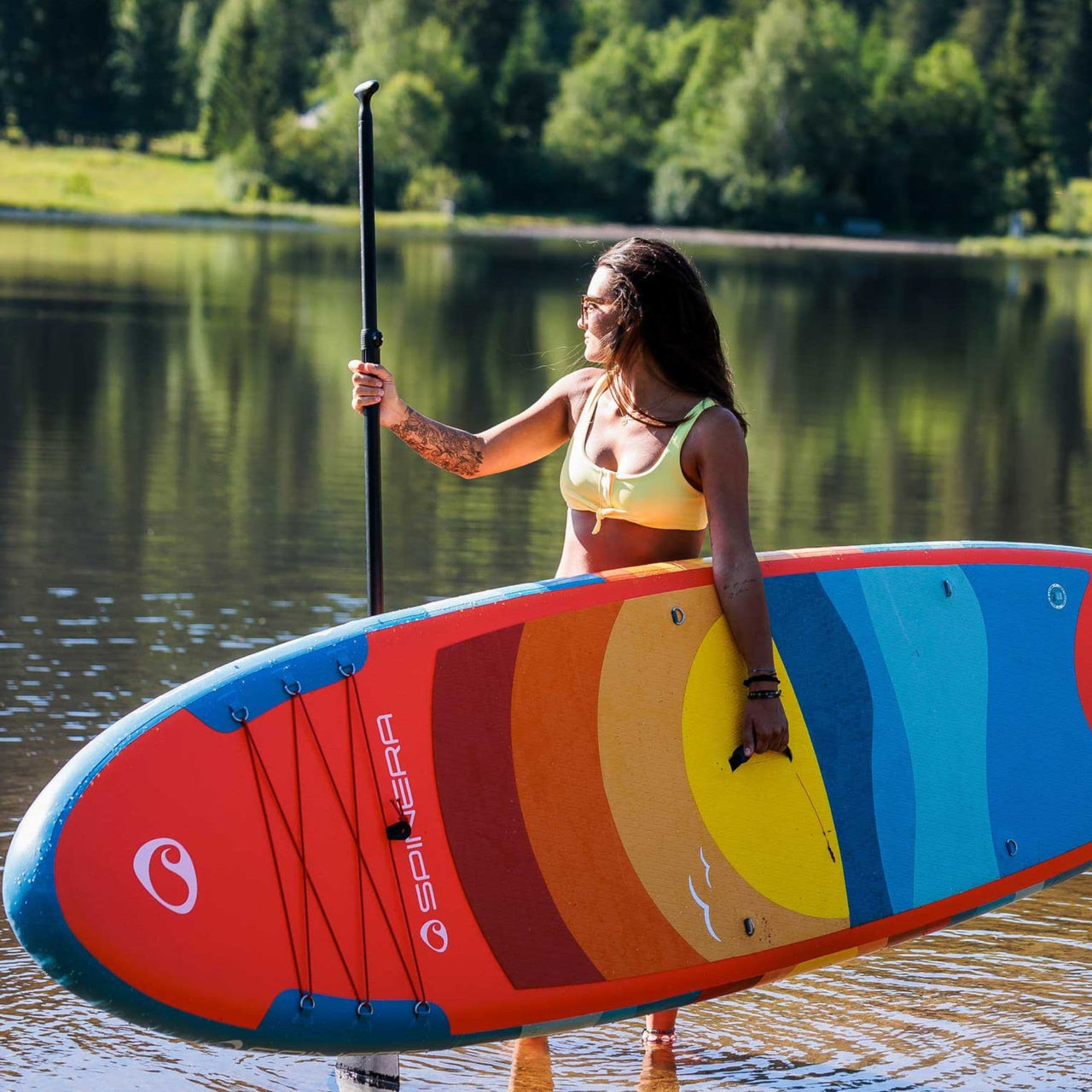 Spinera SUP Supventure Sunset 10.6 With a Woman Holding a Paddle and a Board Looking at the Water