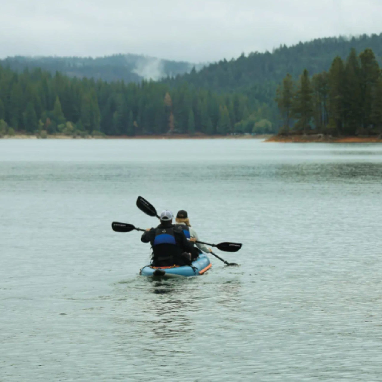 Spinera Tenaya 140 Inflatable Kayak With Two People Kayaking On Calm Lake With Forest View