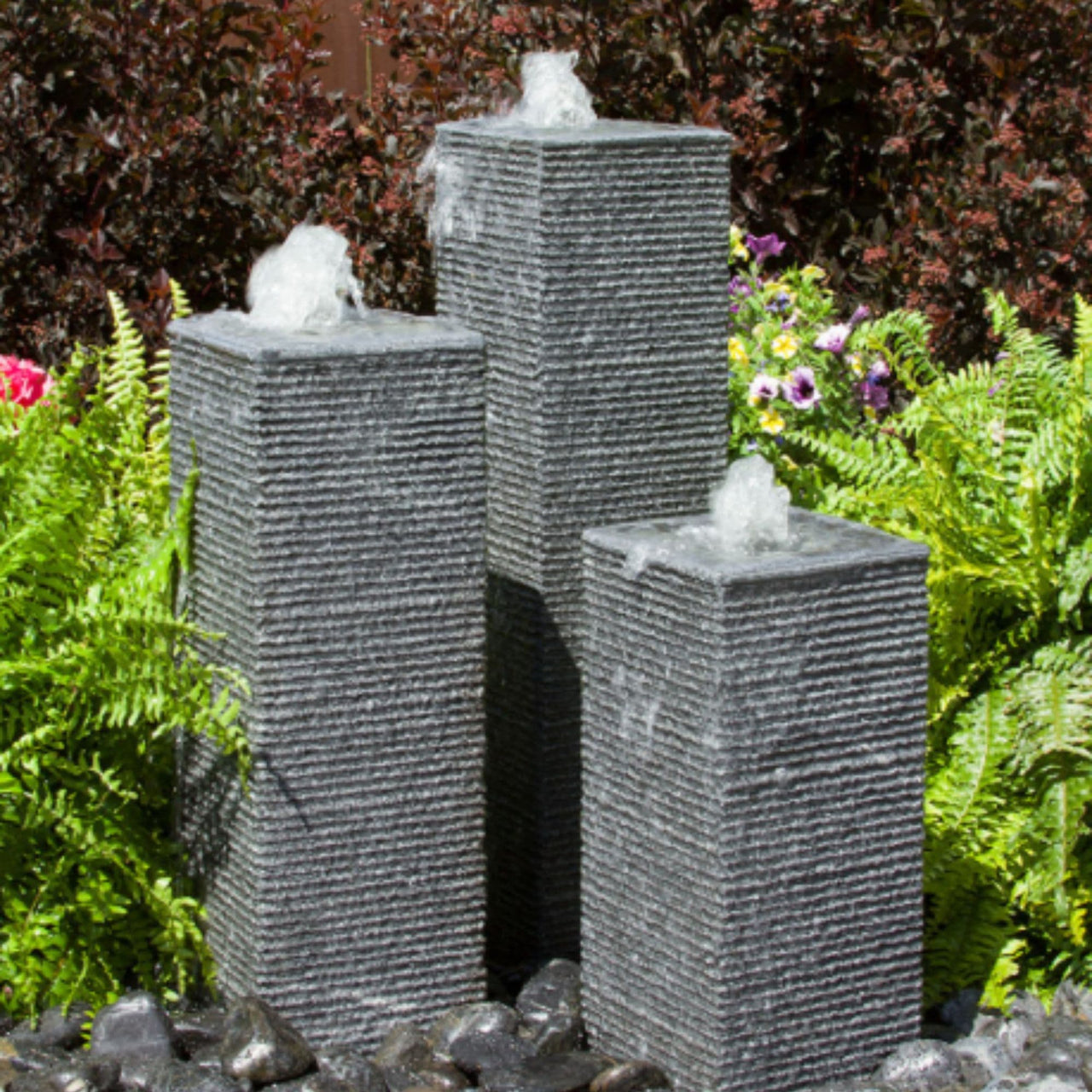 Square Chiseled Stone Towers Outdoor Fountain With Colorful Plants Background
