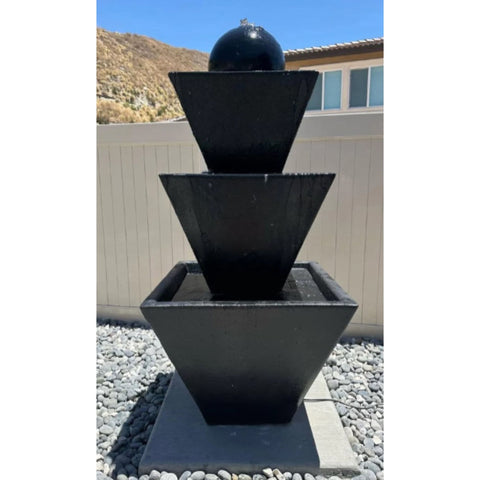 Three Tier Fountain With Ball With Mountain And A House In The Background