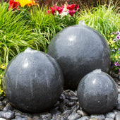 Triple Black Granite Stone Sphere Fountain With A Varity Of Plants In The Background