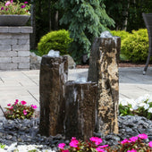Triple Bowled, Polished Top Basalt Column Outdoor Fountain With Flowers And Green Trees Background
