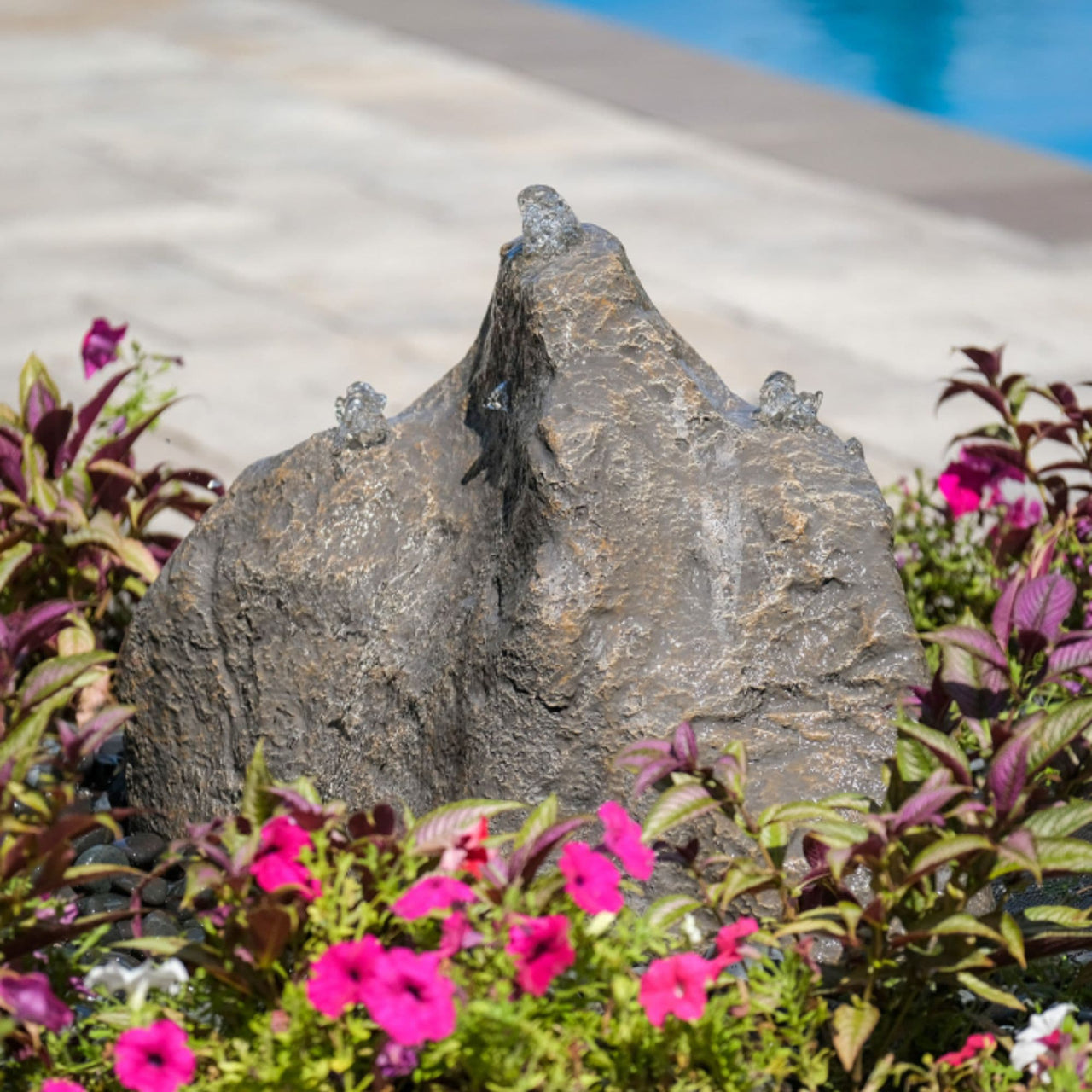 Triple Cascade Stone Outdoor Fountain Surrounded By Colorful Flowers