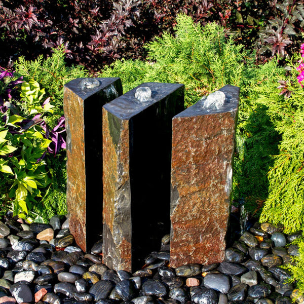 Triple Split Polished Basalt Stone Outdoor Fountain Surrounded By Different Plants