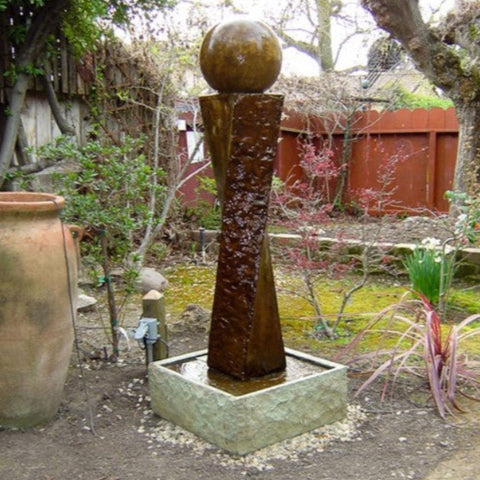 Twist Rock Fountain With Ball Besides The Big Clay Jar With Wooden Fence In The Background