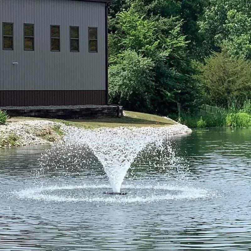 Vanguard Typhoon 3/4 HP Floating Display Aerator On Water With Trees & A Building In The Background