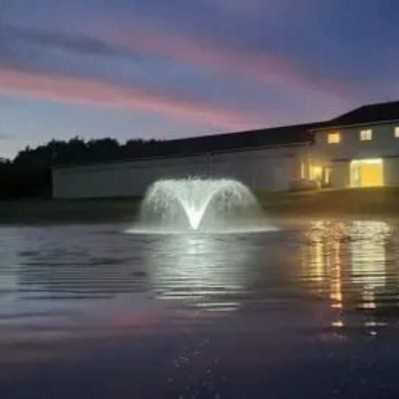 Vanguard Typhoon 3/4 HP Floating Display Aerator With Lights On The Water & A Building In The Background