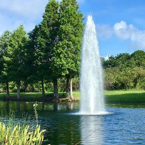 Vertex GeyserJet Floating Pond Fountain With A Green Trees Behind