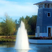 Vertex MultiGeyser Floating Pond Fountain Spraying Waters With Trees And Blue Pondside Tower