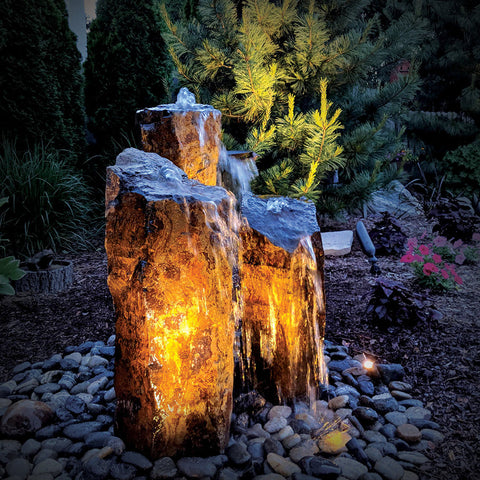 Triple basalt fountain lit with Blue Thumb warm white LED lights at night