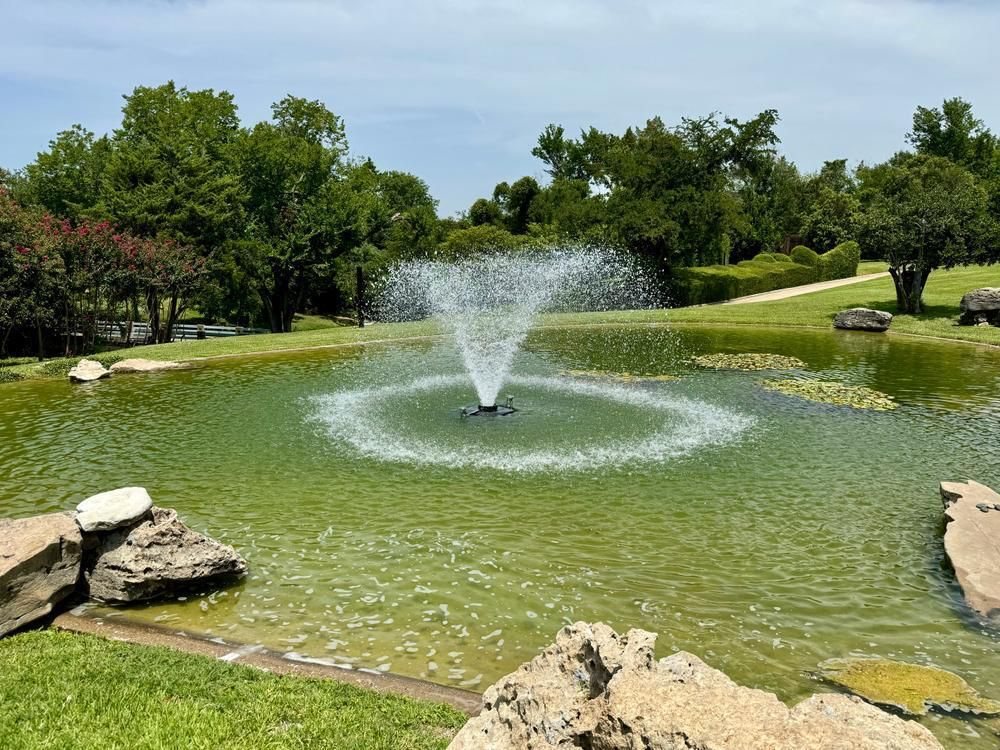 Floating fountain spraying in a landscaped customer pond
